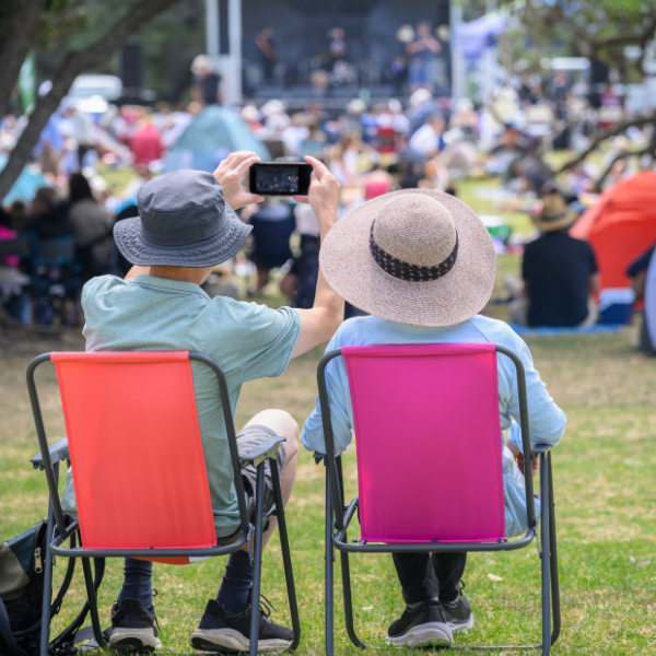 Couple At Concert In Park Taking Picture With Phone 600X600